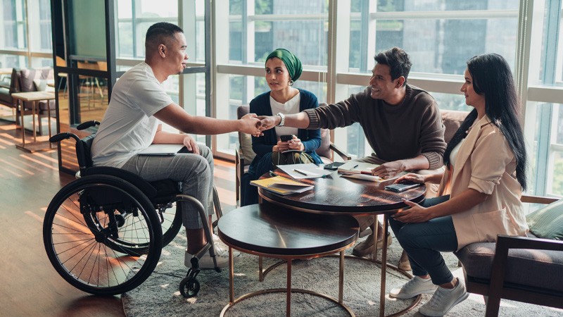 Pessoas com deficiência reunidas em uma sala de reuniões discutindo ideias